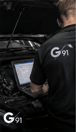 Technicien Garage 91 réalisant un diagnostic électronique sur ordinateur portable, capot ouvert